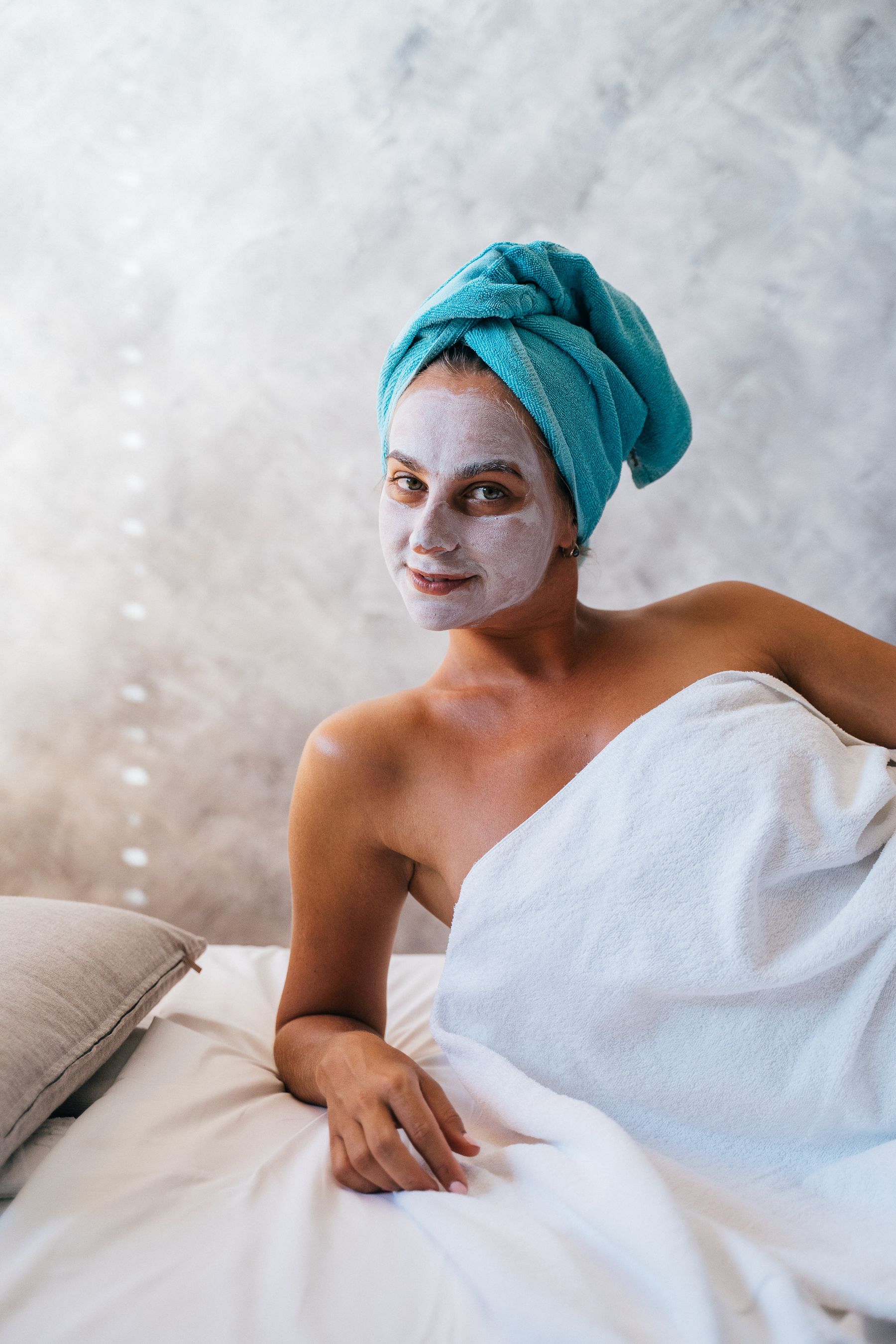 Smiling woman wrapped in a towel with a face mask